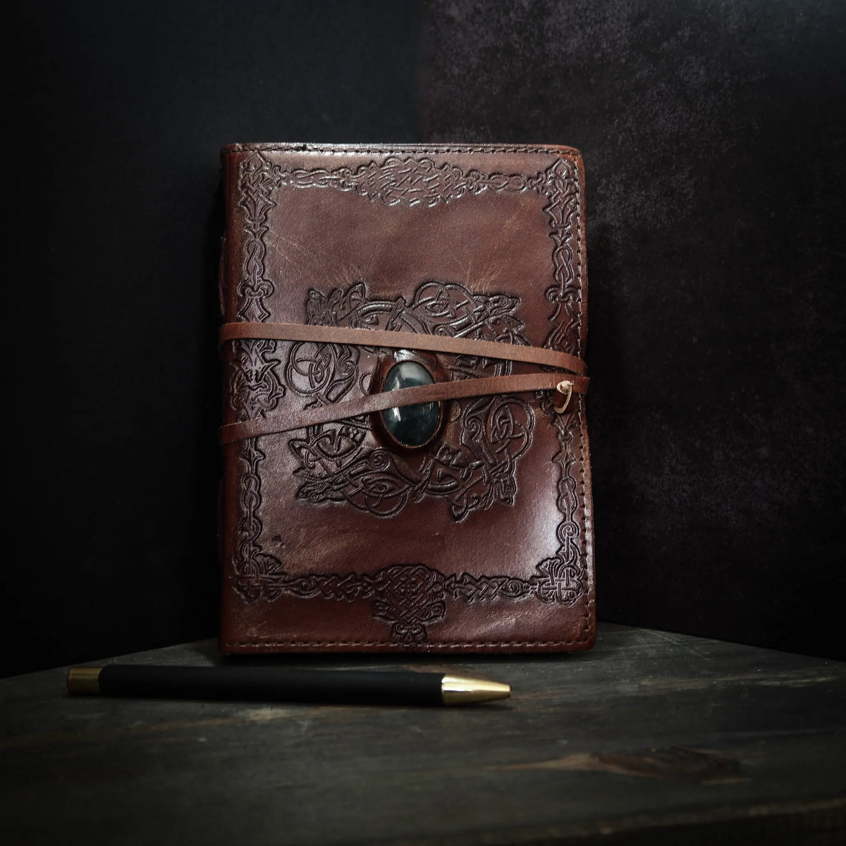 Handgjord läderbok Kristall i medium med moss-agat-sten. Burgundibrunt läder med präglad vikingmönsterkant, grön moss-agat-sten i metallfattning och brunt läderband.