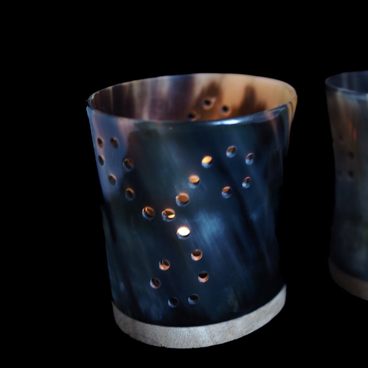 Triskele candle lanterns – a lantern with hole pattern and lit tealight, next lantern glimpsed on the right