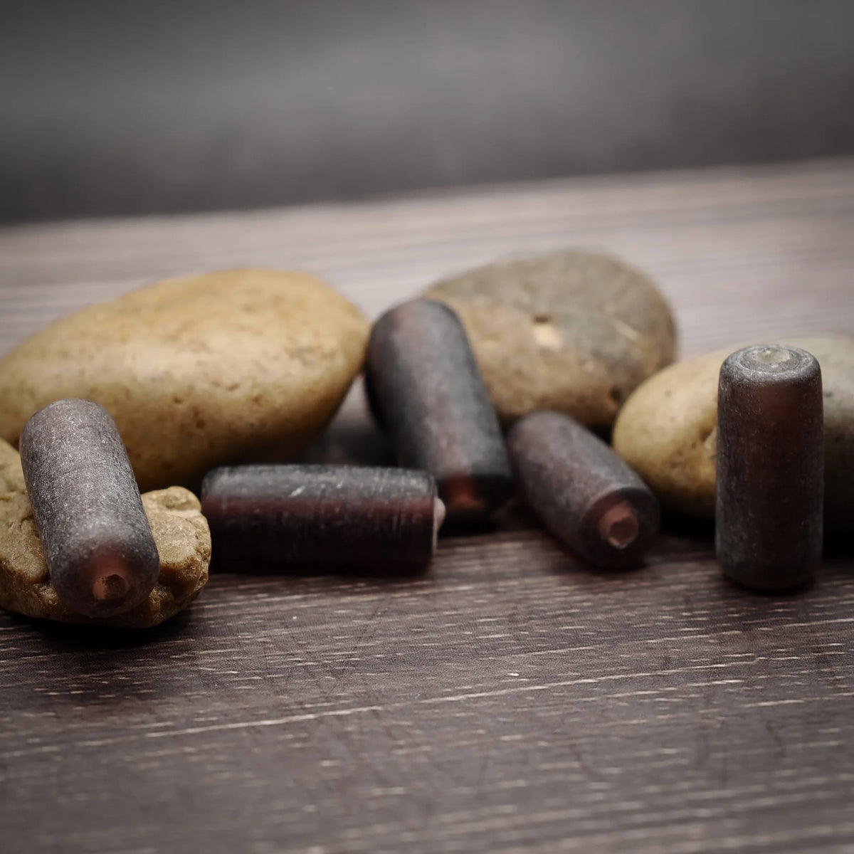 Matt lila glaspärla, avlång form, cirka 20 millimeter. Handgjord pärla med dov lila-grå färg och mjuk mattfinish. Tunnt hål synligt för att trä på snöre eller tråd.