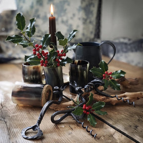 Corkscrew, Elk – two forged corkscrews and a bottle opener on a table among horn mugs and holly