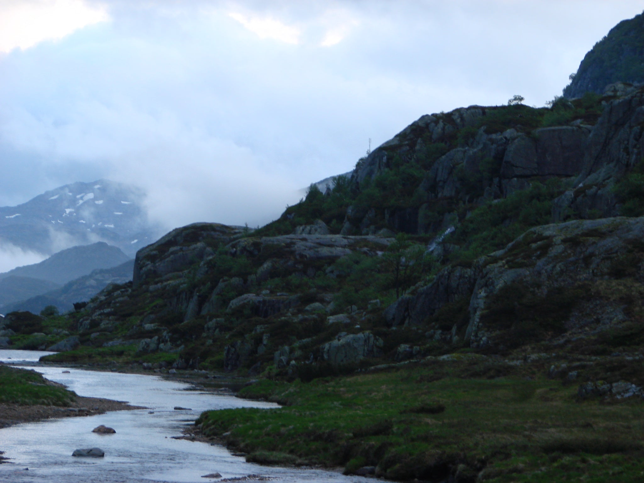 Norwegian mountains and river, clouds are gathering in the back of the mountain range 
