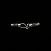 Halsbandslås i silver med S-krok och ornerade ändhylsor mot svart bakgrund