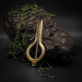 Mungiga traditionell stämd i mässing med varmt metallglans på stenig naturlig bakgrund med mossa och lichen