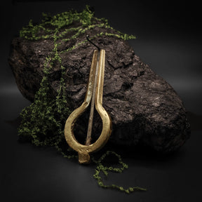 Mungiga traditionell stämd i mässing med varmt metallglans på stenig naturlig bakgrund med mossa och lichen