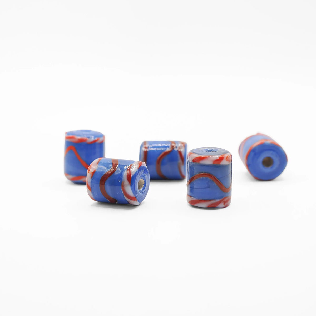 Blå tubformad glaspärla med mönster i rött och vitt.