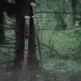 Lofotr Viking sword – sword and leather scabbard with red bindings leaning against a tree outdoors