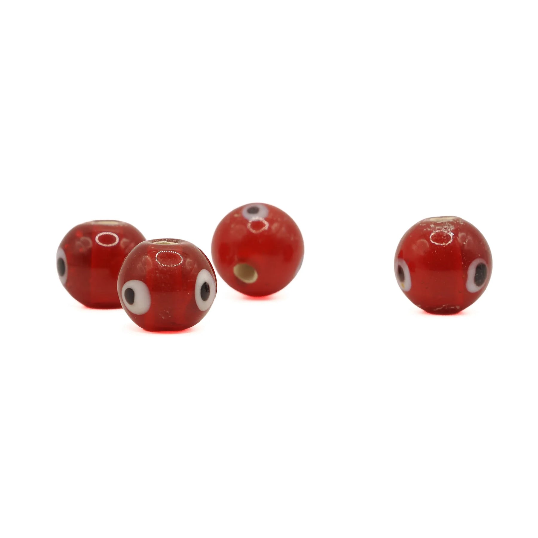 Red glass bead with eye – four beads spread out, eye decoration and a through hole visible