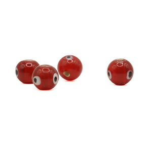 Red glass bead with eye – four beads spread out, eye decoration and a through hole visible