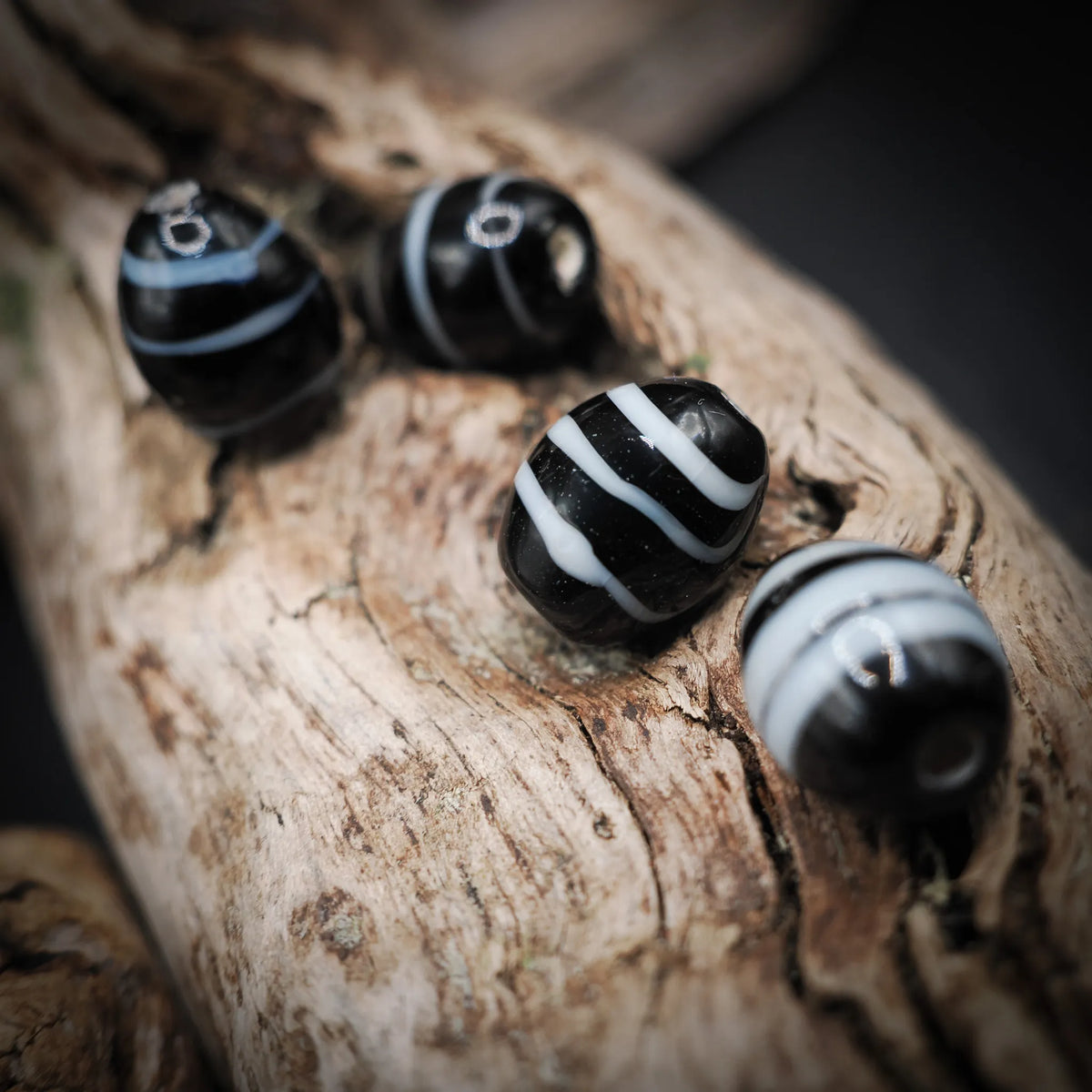 Black and white glass bead – four oval beads with white stripes, holes visible on two