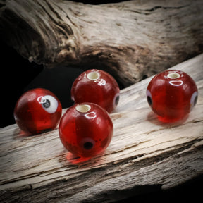 Red glass bead with eye – four beads seen from the side, eye decoration and holes visible