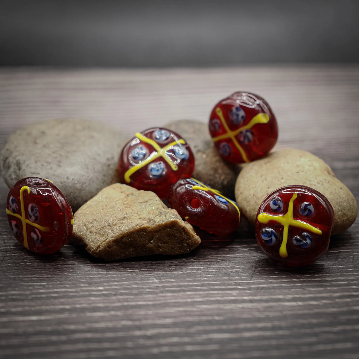 Röd glaspärla med gula och blå mönster