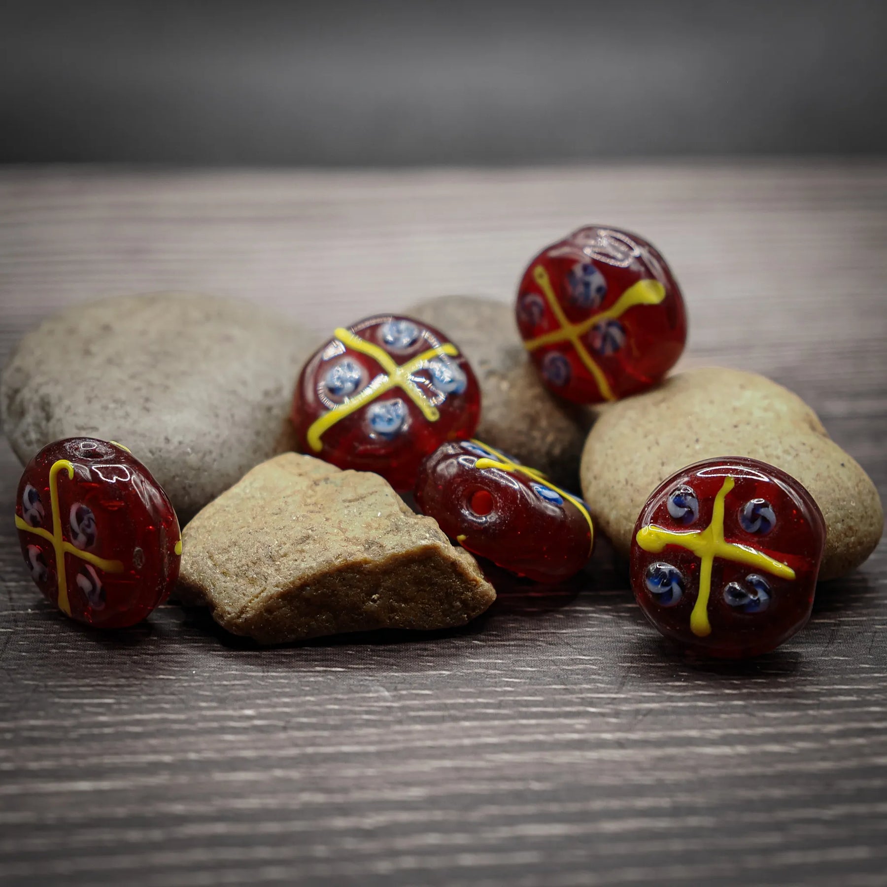 Röd glaspärla med gula och blå mönster