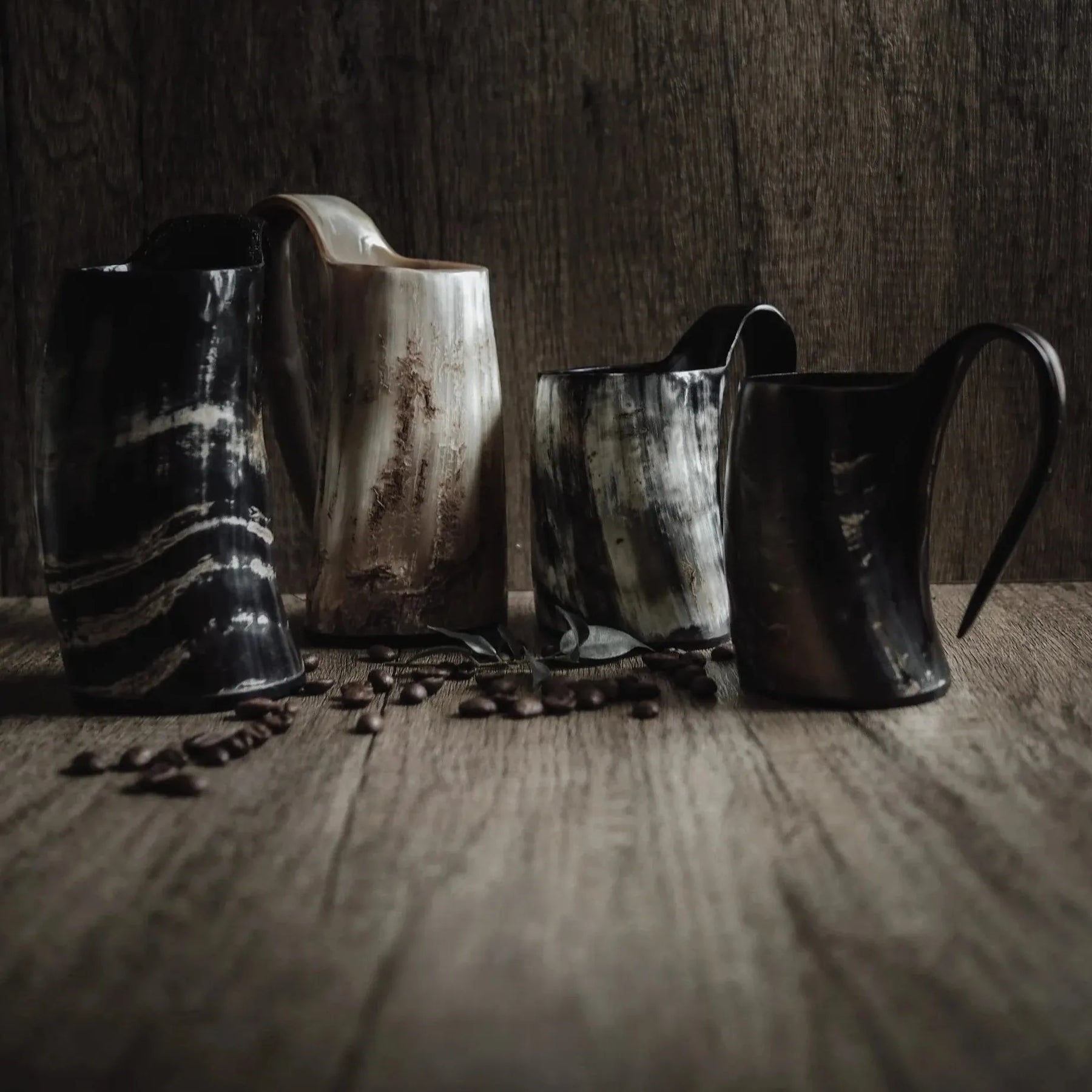 Kaffemugg i horn – fyra muggar i olika nyanser och mönster uppställda bredvid kaffebönor