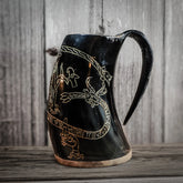 Svart graverad hornmugg med Sigurdsagan-motiv. Runor och figurer från den norska sagan är inskurna runt muggen. Naturligt hornmaterial med trä- och hornbotten.