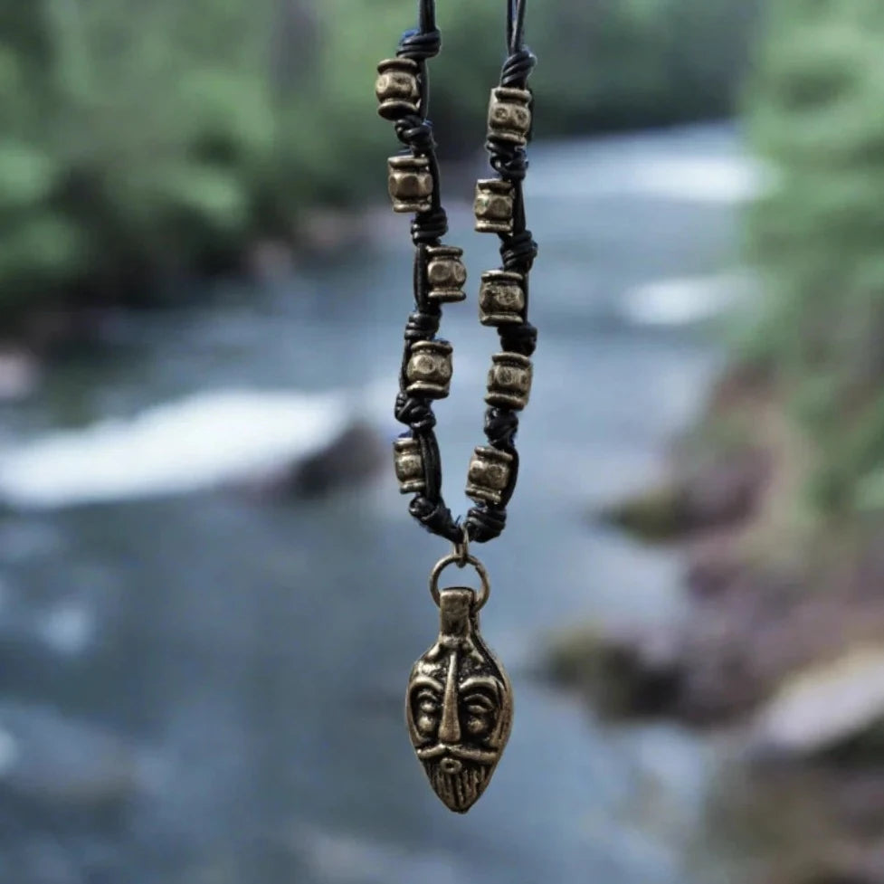 Halsband Odin med gudamask i brons på svart läderband med bronsöglor, visat utomhus vid vattendrag