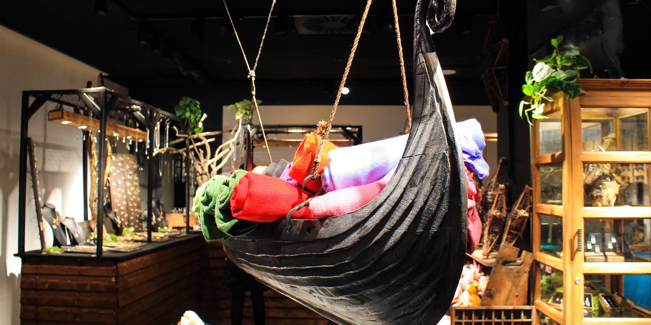 Ett vikingaskepp fylt med ullsjalar hänger från taket i en butik