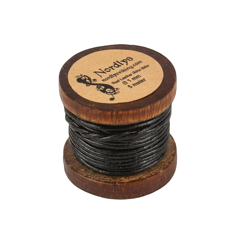Nordlys läderband 5 meter på träspole fotograferat framifrån mot grå bakgrund. Träspolen med präglat varumärke och text på toppen. Svart lädersnöre lindadt tätt runt spolen.