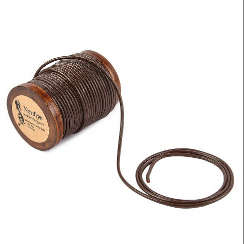Läderband från Nordlys Viking - 2mm tjockt brunt läderband på träspole, 20 meter totalt. Läderband är delvis utrullat från spolen för att visa tjockleken, textur och naturlig läderyta. Vintage träspole med märkning.